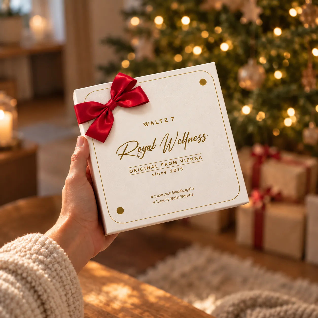 Royal Wellness Badekugeln Geschenkbox mit roter Schleife vor einem Weihnachtsbaum